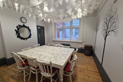 Our Alice's Room, a black and white room with bunting on the ceiling and a table laid out like the Hatter's tea party