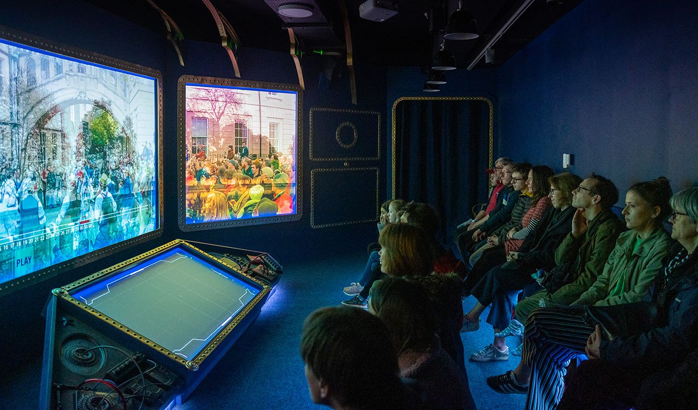 A group of families watching the City of Stories film experience.