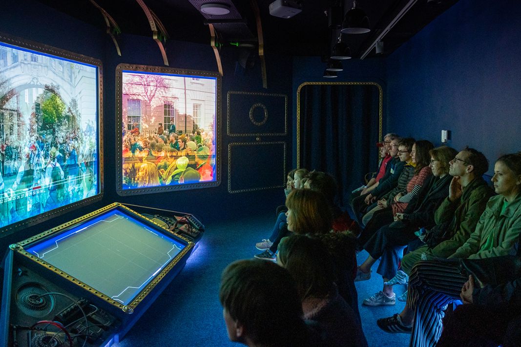 A group of families watching the City of Stories film experience.
