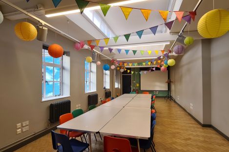 Our long Link Room with colourful bunting on the ceiling and a large table with chairs