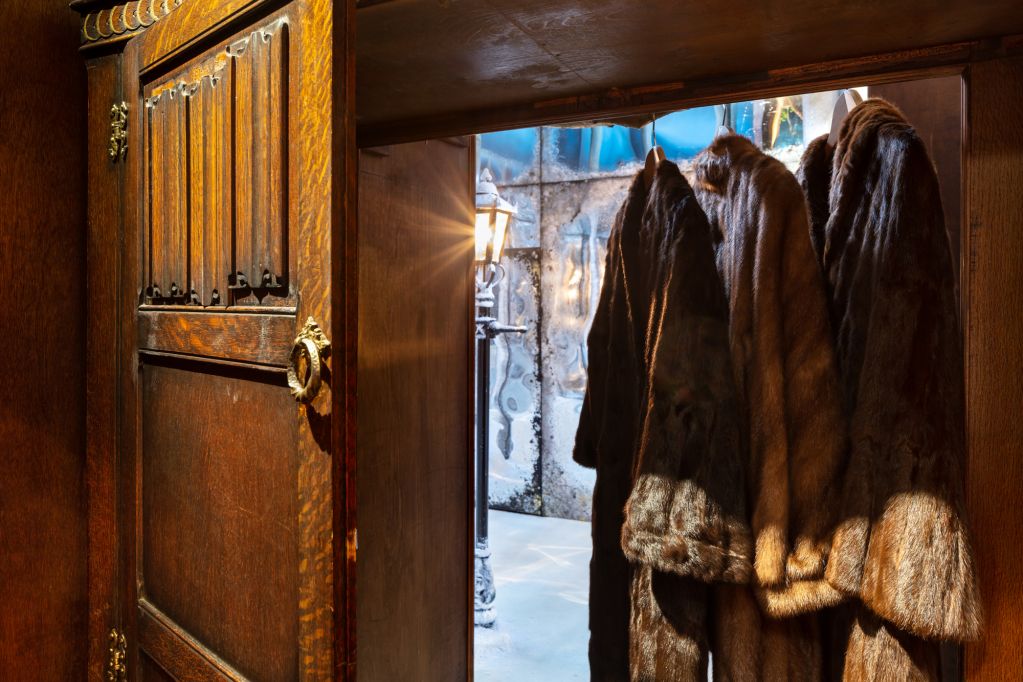 Wardrobe door with fur coats leading into Narnia installation