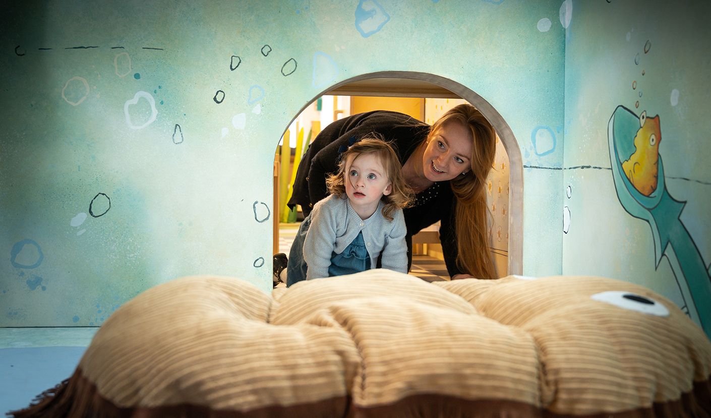 A mum and child peering through an entrance together.