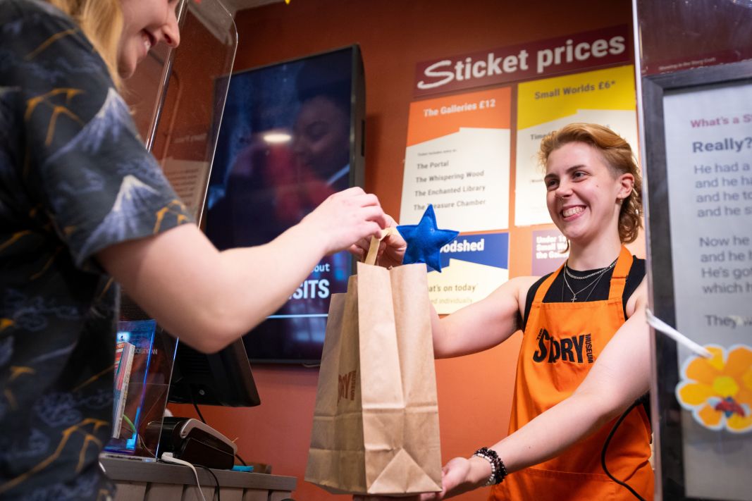 A friendly Visitor Services Assistant serving a customer in our shop