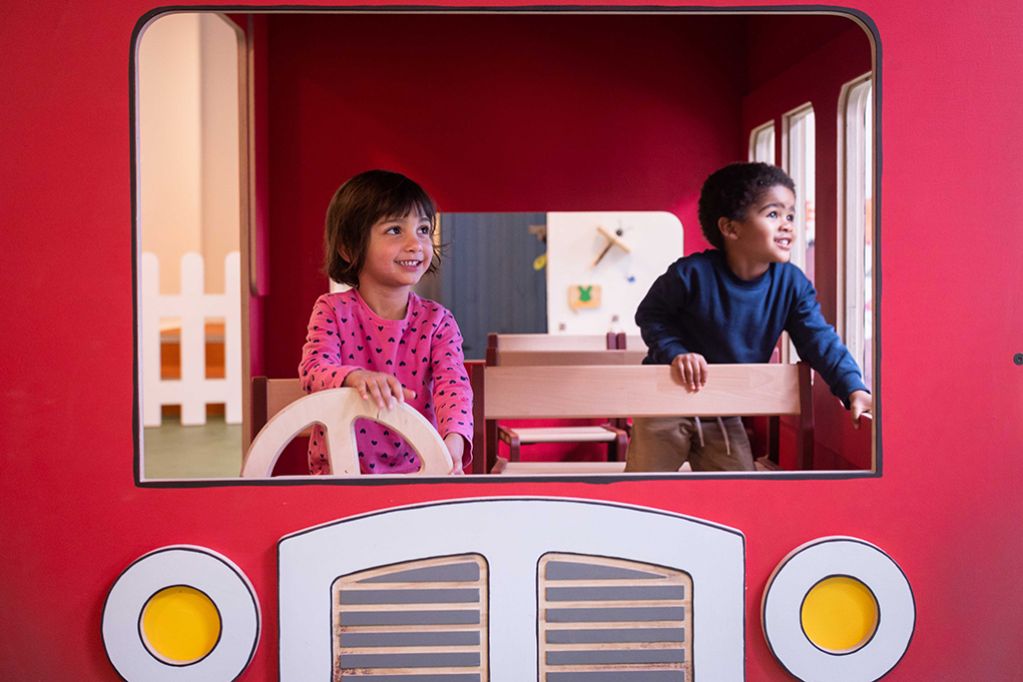 Two children playing on a pretend bus.