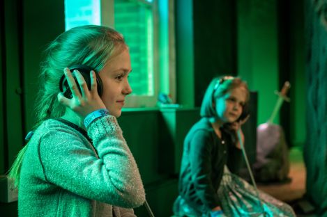 Two children holding speaker cups to their ears