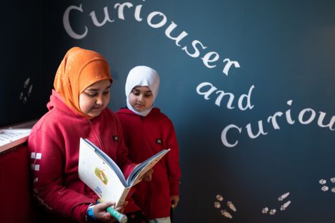 Two students looking at a book in the Alice in Wonderland story installation